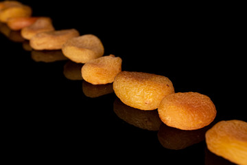 Group of nine whole dried orange apricot isolated on black glass