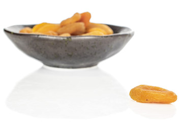 Lot of whole dried orange apricot in glazed bowl isolated on white background
