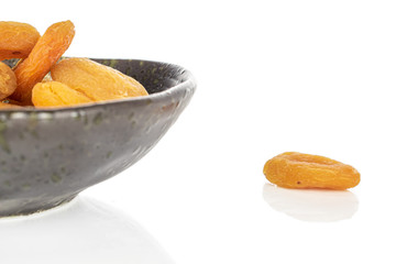 Lot of whole dried orange apricot closeup in glazed bowl isolated on white background