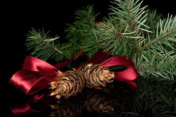 Lot of whole decorated christmas green branch spruce with red ribbon isolated on black glass