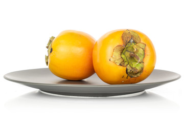 Group of two whole sweet orange persimmon on gray ceramic plate isolated on white background