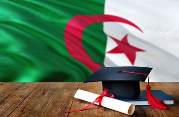 Algeria education concept. Graduation cap and diploma on wooden table, national flag background. Succesful student.