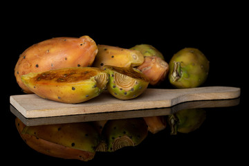 Group of four whole two halves of prickly green opuntia on wooden cutting board isolated on black glass