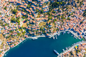 Aerial drone bird's eye view shot of scenic small town and Harbor with ships and yachts traditional Greek style white houses and the seaport with docked boats, island