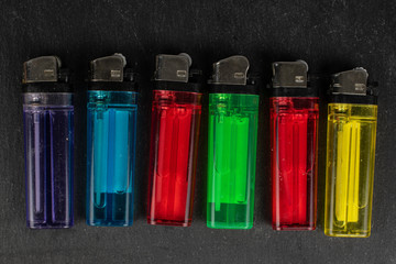 Group of six whole plastic lighter flatlay on grey stone