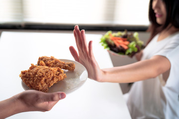 Girl rejecting junk food or unhealthy food choosing healthy food such as green salad for having a good health.