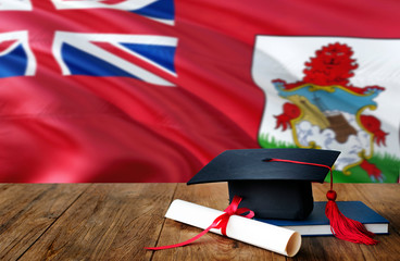 Bermuda education concept. Graduation cap and diploma on wooden table, national flag background. Succesful student.