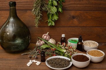 some plants, bulbs and medicinal seeds, with a rustic wooden background, and some bottles, as a concept of alternative medicine and disease prevention and health promotion, in a natural way