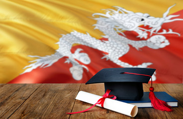 Bhutan education concept. Graduation cap and diploma on wooden table, national flag background. Succesful student.