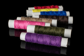 Group of eight whole sewing thread spool isolated on black glass