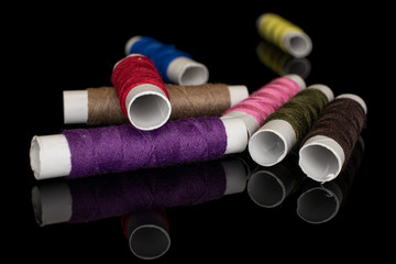 Group of eight whole sewing thread spool isolated on black glass