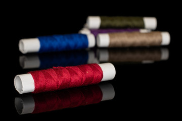 Group of five whole sewing thread spool isolated on black glass