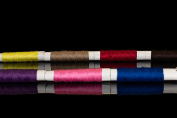 Group of seven whole sewing thread spool isolated on black glass