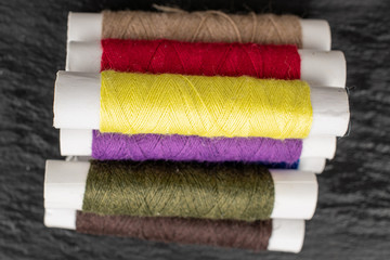 Group of six whole sewing thread spool flatlay on grey stone