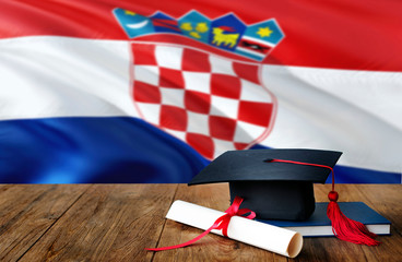 Croatia education concept. Graduation cap and diploma on wooden table, national flag background....