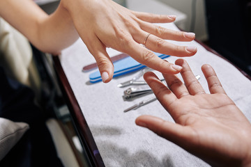 Close-up image of young woman giving her hand with old manicure to beauty salon worker