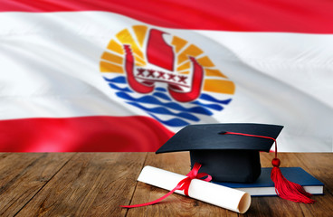 French Polynesia education concept. Graduation cap and diploma on wooden table, national flag background. Succesful student.