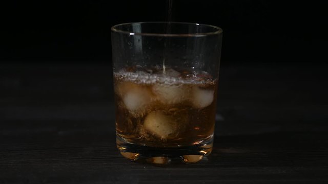 Video of pouring whiskey into a glass with ice