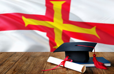 Guernsey education concept. Graduation cap and diploma on wooden table, national flag background....