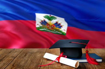 Haiti education concept. Graduation cap and diploma on wooden table, national flag background. Succesful student.