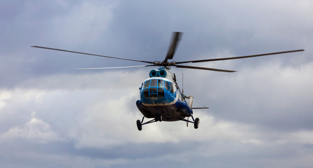 Helicopter in blue and white colors against a cloudy sky.