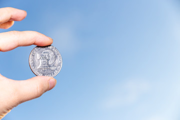 hand holding 1 dollar coin over clear blue sky, Exchange money. Financial concepts, Business Concept.
