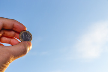 hand holding 1 euro coin over clear blue sky, Exchange money. Financial concepts, Business Concept.