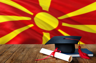 Macedonia education concept. Graduation cap and diploma on wooden table, national flag background. Succesful student. - obrazy, fototapety, plakaty