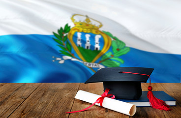San Marino education concept. Graduation cap and diploma on wooden table, national flag background....