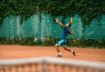 Tennis player swings a racket to make a serve shot.