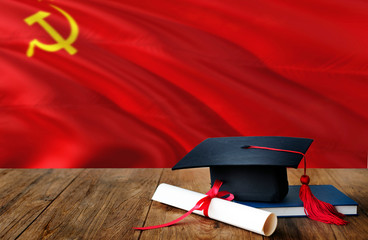 Soviet Union education concept. Graduation cap and diploma on wooden table, national flag background. Succesful student.