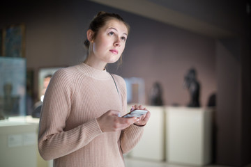 Female visitor  touching  phone  in the historical museum