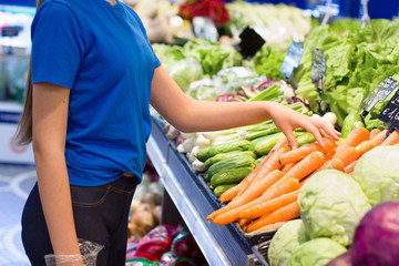 Teen girl shopping in supermarket, reading product information. Choosing daily product. Concept of healthy food, bio, vegetarian, diet.