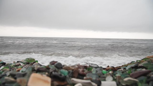 The famous beach with glass fragments stones in Russky Island, Vladivostok. Waves come to land. Environmental pollution