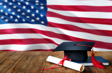 United States education concept. Graduation cap and diploma on wooden table, national flag...