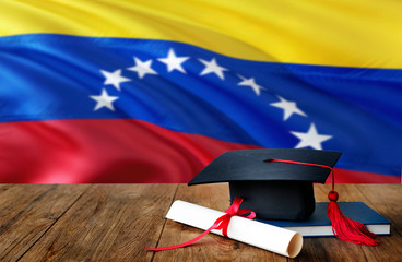 Venezuela education concept. Graduation cap and diploma on wooden table, national flag background. Succesful student.