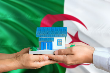 Algeria real estate concept. Man and woman holding miniature house in hands. Citizenship theme and...