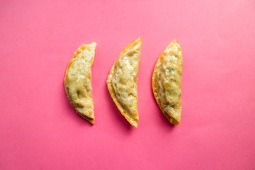 Fried mandu filled with beef, pork and shrimps on pink background. Korean cuisine.