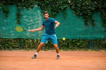 Skilled and agile tennis player having a practice at outdoor court.