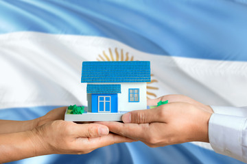 Argentina real estate concept. Man and woman holding miniature house in hands. Citizenship theme...