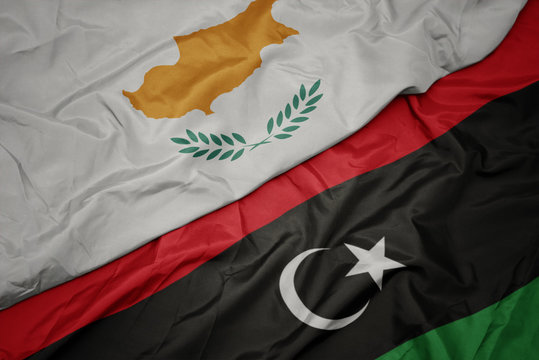 waving colorful flag of libya and national flag of cyprus.