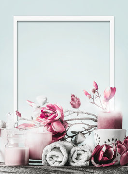 Wellness frame with body care cosmetic products, candles, flowers and towels at light blue background with copy space. Healthy still life. Spa layout