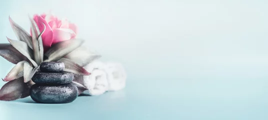Deurstickers Spa- en wellness-concept met stapel zen-stenen, bloemen en handdoeken op een lichtblauwe achtergrond met kopieerruimte. Ontspan en kalme behandeling. Stilleven. Banner © VICUSCHKA