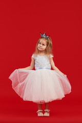 Joyful little girl with long hair in a tulle skirt and princess sparkling crown on her head...