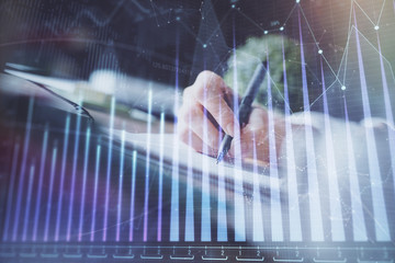 Financial forex graph displayed on hands taking notes background. Concept of research. Multi exposure