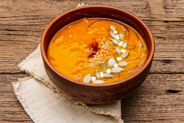 Autumn pumpkin cream soup. Traditional ingredients, healthy food concept. Napkin, vintage wooden background