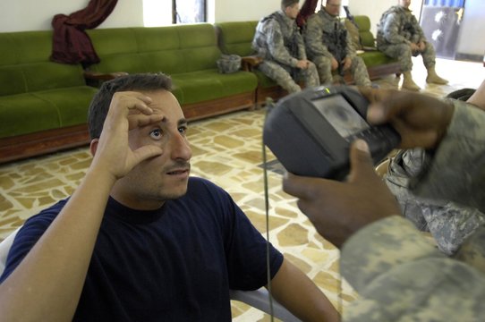 An Iraqi candidate for the Sons of Iraq security force holds his eye open for a retinal scan administered by a US Soldier in Wasit Province Iraq