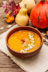 Autumn pumpkin cream soup. Traditional ingredients, healthy food concept. Napkin, vintage wooden background