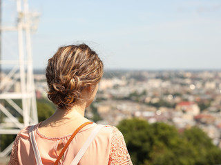 A girl looks into the distance from a height at the historical center of ancient Lviv. The skeleton...