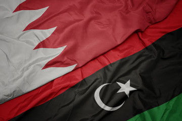 waving colorful flag of libya and national flag of bahrain.